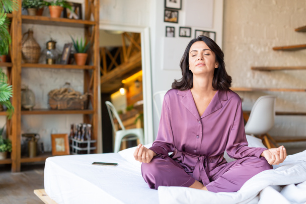 Geestelijke gezondheid en digitale detox concept - vrouw van middelbare leeftijd mediteren in bed. - Foto, afbeelding