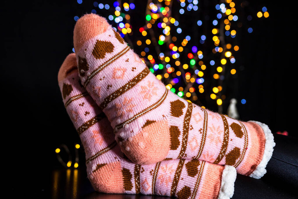A closeup of female feet in Christmas socks with bokeh lights background - Foto, afbeelding