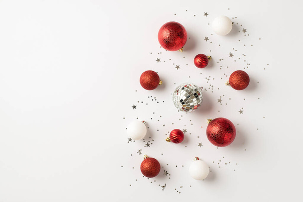 Top pohled fotografie červené a bílé vánoční stromky dekorace disco koule a stříbrné konfety na izolovaném bílém pozadí s prázdným prostorem - Fotografie, Obrázek