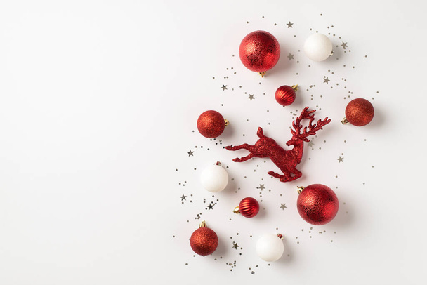 Top pohled fotografie červených a bílých vánoční stromeček dekorace koule sobi a stříbrné konfety na izolovaném bílém pozadí s copyspace - Fotografie, Obrázek