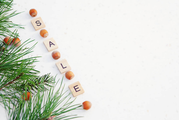 英語の販売でテキストとクリスマスの組成。松の緑の枝、白い背景のヘーゼルナッツ、フレーム。クリスマスの背景、トップビュー、水平画像、コピースペース - 写真・画像