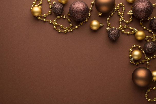Foto vista superior de las decoraciones del árbol de navidad bolas doradas y marrones y guirnalda de barba de oro sobre fondo marrón aislado con espacio vacío - Foto, Imagen