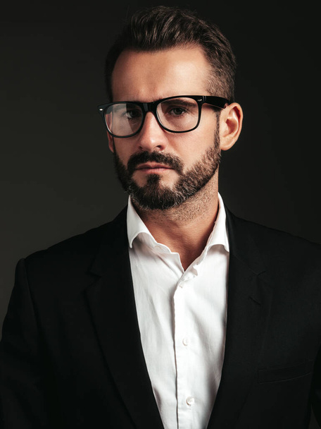 Closeup portrait of handsome confident stylish hipster lambersexual model. Sexy modern man dressed in elegant black suit. Fashion male posing in studio on dark background. In spectacles - Fotografie, Obrázek