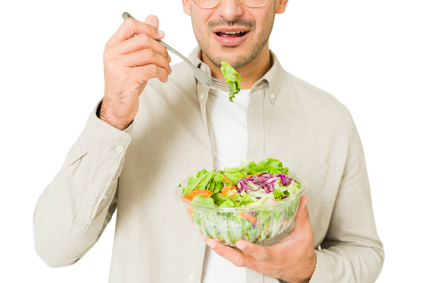 Zbliżenie Latynosa jedzącego zieloną sałatkę na lunch. Odpowiedni młody człowiek ze zdrową dietą - Zdjęcie, obraz