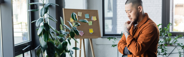 pensivo asiático empresário pensamento perto borrado plantas e nota bordo no escritório, banner - Foto, Imagem