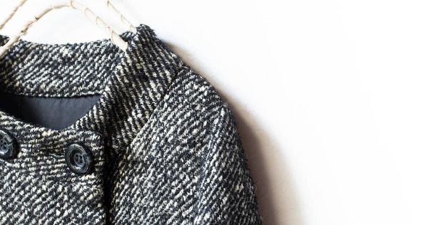 black and white wool coat hanging on clothes hanger on white background.Close up. - 写真・画像