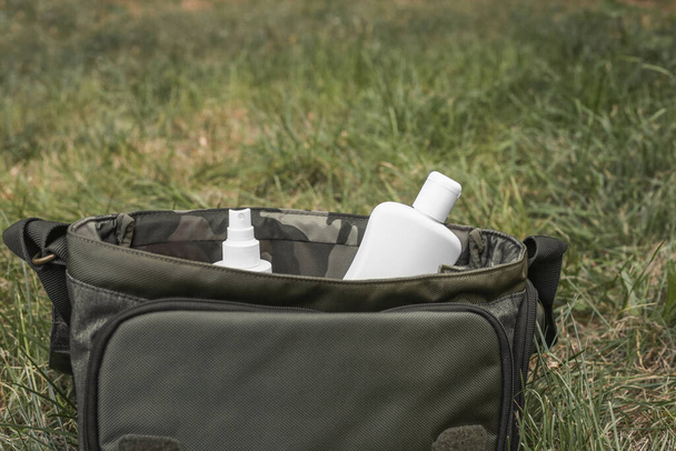 Jars of mosquito repellent and suncream in a travel bag outdoors. - Fotografie, Obrázek