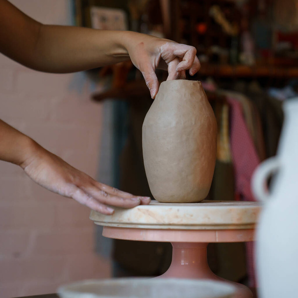 Δημιουργία κεραμικής: γυναίκα καλλιτέχνης που διαμορφώνει αγγείο γλυπτικής από ακατέργαστο πηλό. Κορίτσι τεχνίτης στην εργασία - Φωτογραφία, εικόνα
