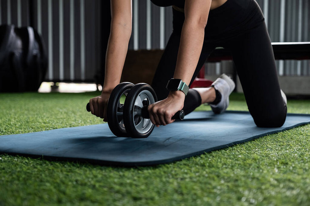 Nahaufnahme Hand von asiatischen Sportlerin macht ab Roller-Übung während der Arbeit auf Fitness-Center Hintergrund. Konzept Frauengesundheit. - Foto, Bild