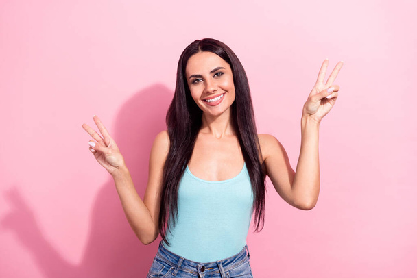 Photo portrait of brunette cheerful showing v-sign gesture isolated on pastel pink color background - Foto, afbeelding