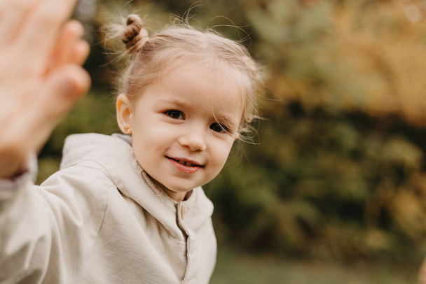 Porträt eines kleinen süßen Mädchens, das die Palme im Herbstpark zeigt - Foto, Bild