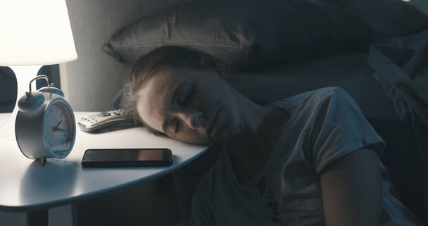 Виснажена жінка лежить на голові на тумбочці і спить пізно вночі
 - Фото, зображення