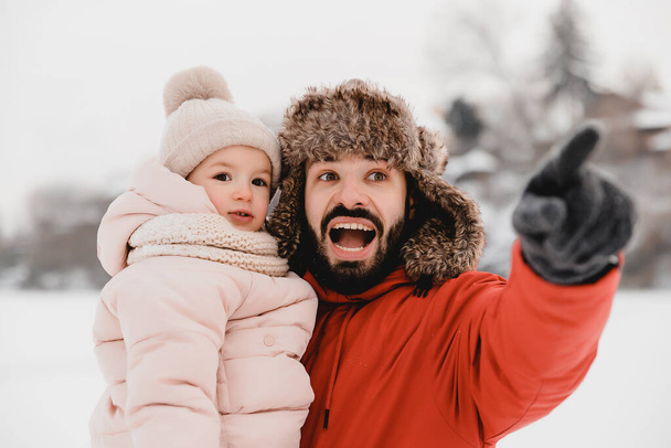 Happy father and baby son having fun under sunny winter snow, holiday season - Foto, Bild