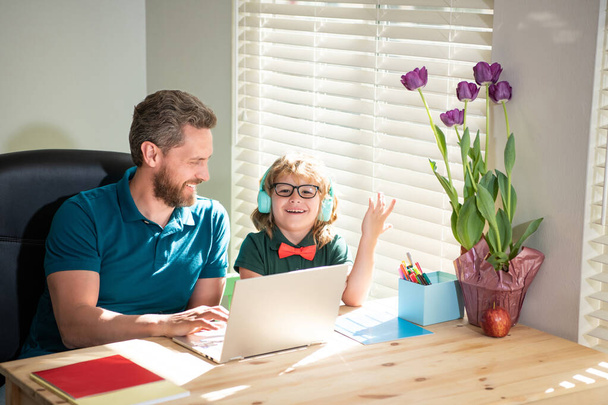 szczęśliwy ojciec pomaga synowi szkoły w nauce słuchawek z laptopem w domu, z powrotem do szkoły - Zdjęcie, obraz