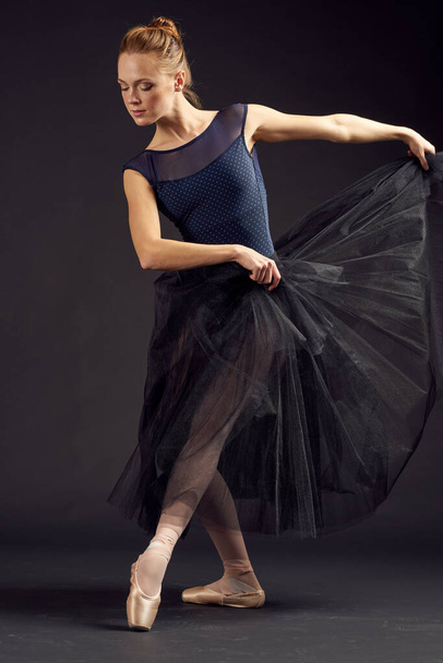 beautiful woman in a black dress dance fashion exercise dark background - Фото, изображение