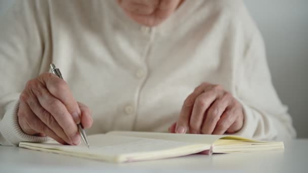 Mulher velha escreve notas com mão trêmula tira óculos - Filmagem, Vídeo