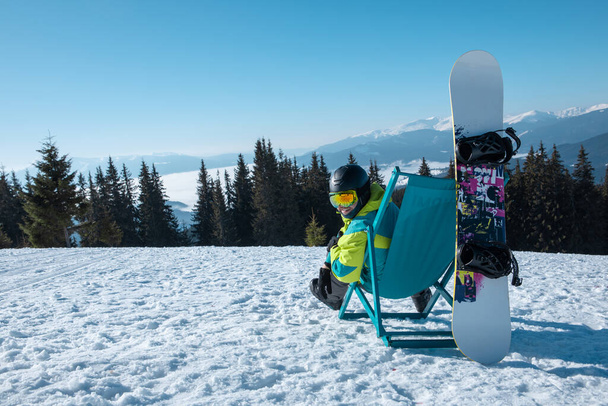 hombre snowboarder sentado en silla disfrutando de las montañas ver copia de espacio - Foto, Imagen