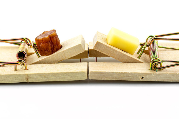 Makro fotografie kostky sýra a kusu masa kabanosy ležícího v pasti na myši, izolovaného na bílém pozadí. - Fotografie, Obrázek
