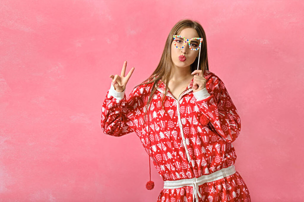 new year portrait of a cheerful girl in pajamas and glasses. pink background - Foto, Imagen
