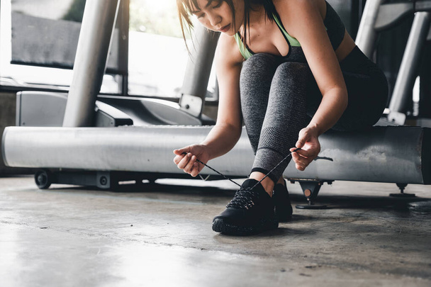 Gros plan de la jeune femme asiatique laçage chaussures de sport avant l'exercice à la salle de gym. - Photo, image