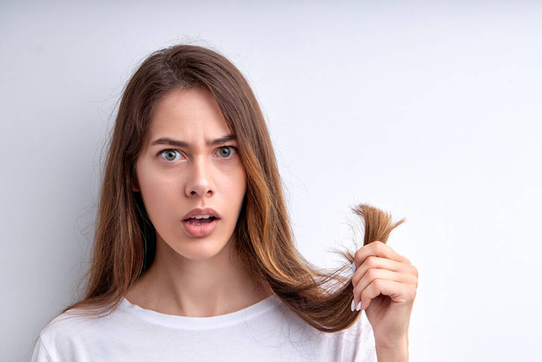 Shocked frustrated woman holding hair in hands, want to cut them out, having split ends - Zdjęcie, obraz