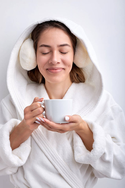 Nice pleasant woman holding mug in hands, drinking tea or coffee, isolated on white - Фото, зображення