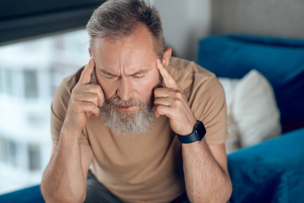 A mature bearded man suffering from a headache - Foto, imagen