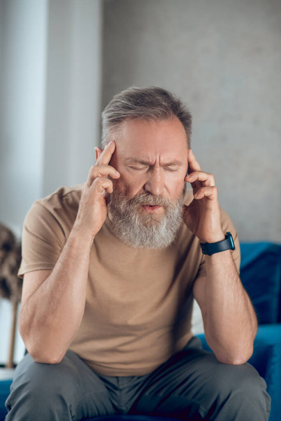 A mature bearded man suffering from a headache - Fotoğraf, Görsel