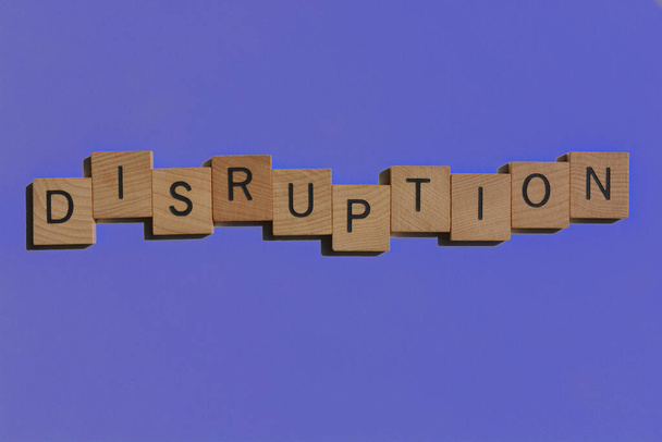 Verstoring, woord in houten alfabet letters geïsoleerd op paarse achtergrond als banner headline - Foto, afbeelding
