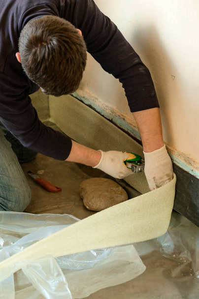 Demping tape ter verbetering van de kwaliteit en duurzaamheid van vloerdekvloer, een nieuwigheid in de bouw, reparatie in een particulier huis. - Foto, afbeelding