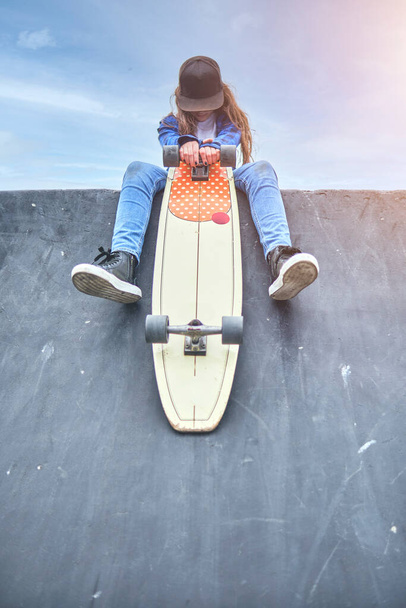 Meisje dat plezier heeft met skateboarden in skate park, Portret van lachende jonge vrouwelijke skateboarder die haar skateboard vasthoudt. Recreatief activiteitsconcept. - Foto, afbeelding