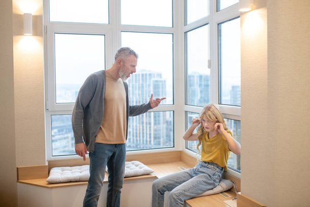 A gray-haired man having a hard talk with his teenage daughter - Φωτογραφία, εικόνα