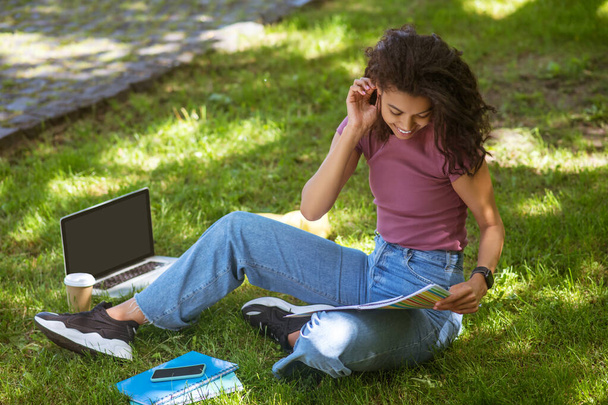 Tyttö rennoissa vaatteissa istuu nurmikolla puistossa ja opiskelee - Valokuva, kuva