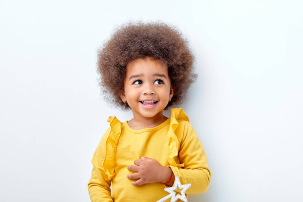 cheerful fluffy african american girl looking happy holding magic wand in hands - Foto, afbeelding