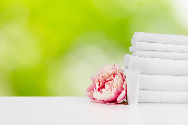 Spa still life with towels and skincare cosmetics against blurred background - 写真・画像