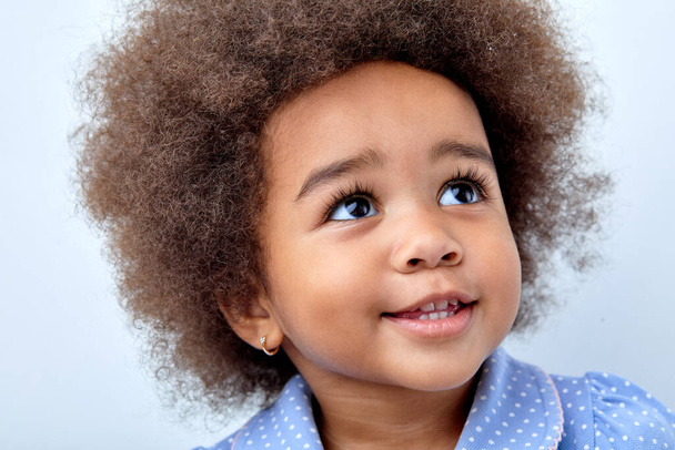 Close up portrait of little adorable African american child girl looking up, smiling - Fotografie, Obrázek