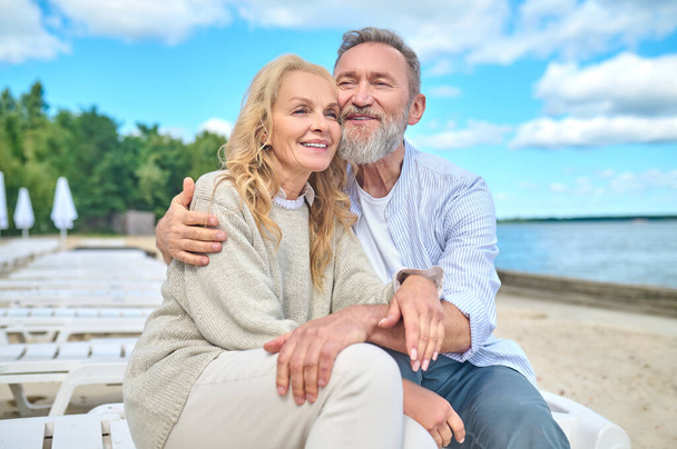 Smiling man and woman sitting on sea beach - Φωτογραφία, εικόνα