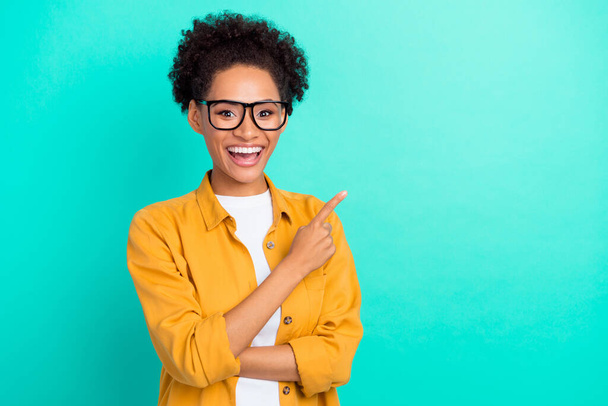 Photo portrait girl wearing glasses cheerful pointing finger copyspace isolated vivid teal color background - Φωτογραφία, εικόνα