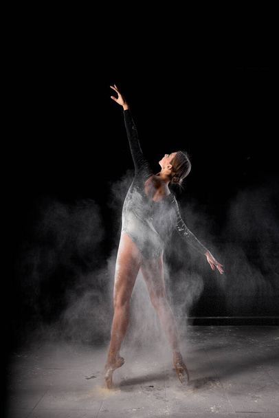 Artistic dance pose using powder or dust. Beautiful expressive ballet dancer in dust - Фото, изображение