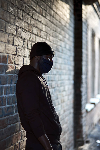 young afro american man in black mask standing at street waiting for victim - Photo, image