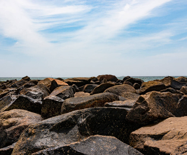 Cielo azul con nubes tenues sobre la bahía de Narragansett con grandes rocas que protegen la costa. - Foto, imagen