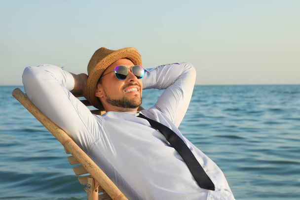 Happy man resting on deckchair near sea. Business trip - 写真・画像