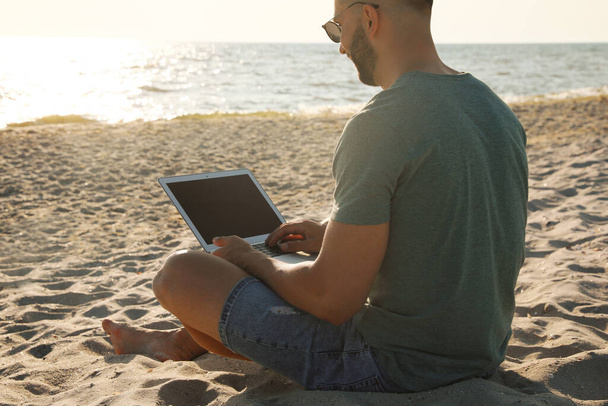 Man working with modern laptop on beach, closeup - Photo, Image