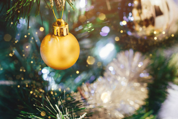 Kultainen pallo koristeltu joulukuusi hämärä valot bokeh. Valikoiva keskittyminen. Lomakortti, jossa koristeet uudenvuodenaattona - Valokuva, kuva