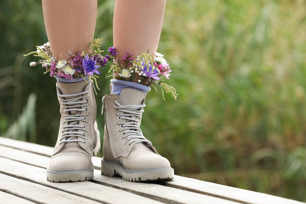Woman standing on wooden pier with flowers in socks outdoors, closeup. Space for text - Fotó, kép