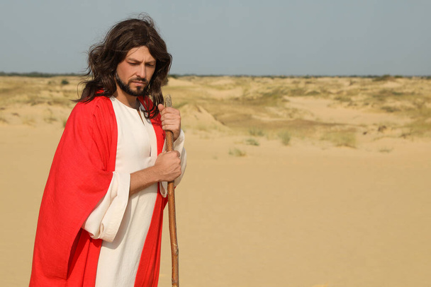 Jesus Christ walking with stick in desert. Space for text - Foto, afbeelding