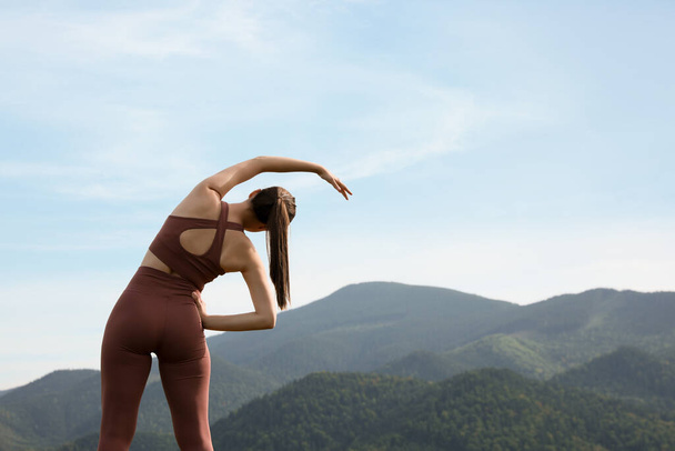 Woman doing morning exercise in mountains, back view. Space for text - Foto, immagini
