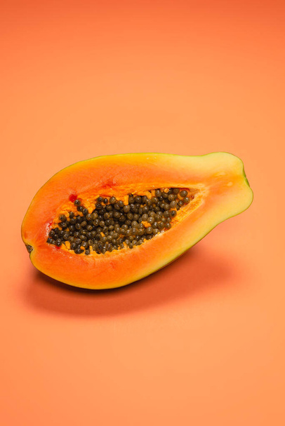 オレンジ色の背景にパパイヤの果物。熱帯果実。半パパイヤ.  - 写真・画像