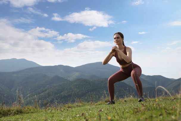 Young woman doing morning exercise in mountains, space for text - Foto, Bild
