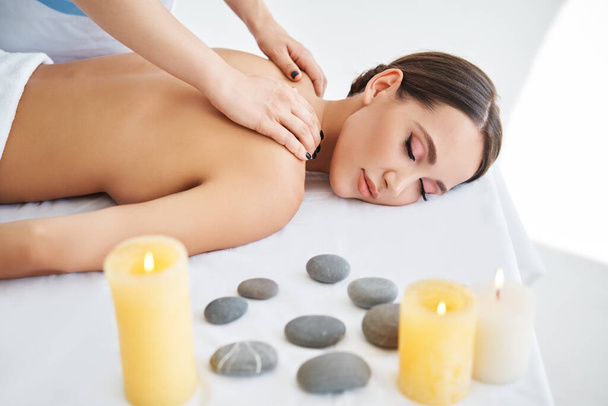 Mujer joven disfrutando de relajante masaje de espalda en el salón de spa - Foto, Imagen